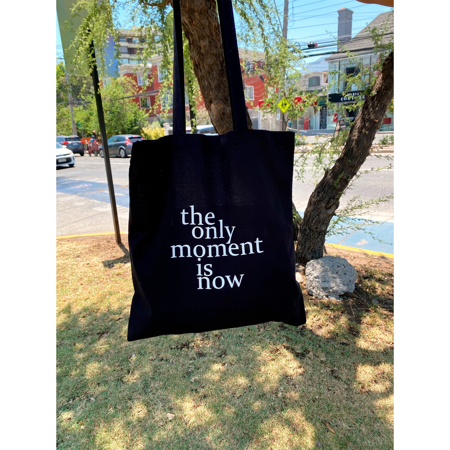 Bolsa de tela color negro con diseño de frase the only moment is now en vinilo textil de tacto suave.